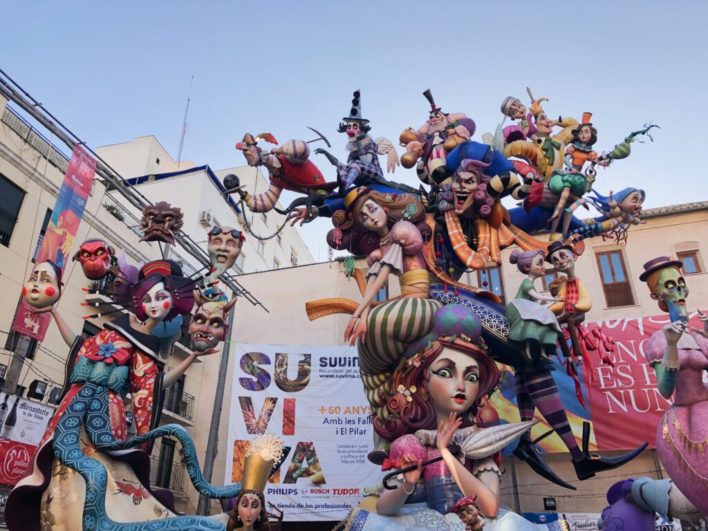 Straatbeeld van Las Fallas festival in Valencia met indrukwekkende kleurrijke beelden, vuurwerk en traditionele festiviteiten, omringd door toeschouwers die de sfeer en cultuur van dit jaarlijkse evenement ervaren.
